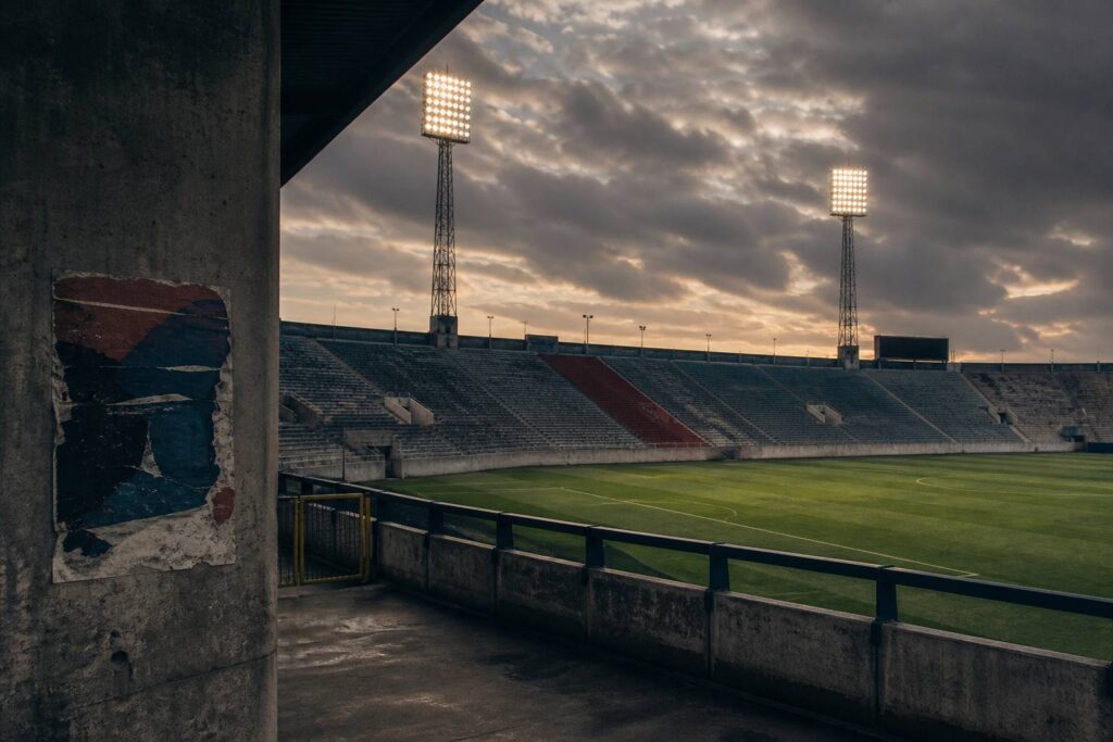 Stade de football avec pelouse et tribunes sous la lumière du soir